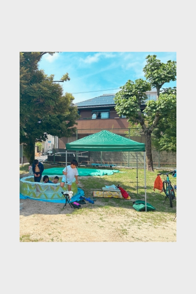 名古屋の公園でプール遊びを楽しむ子どもたちと見守る大人たち。