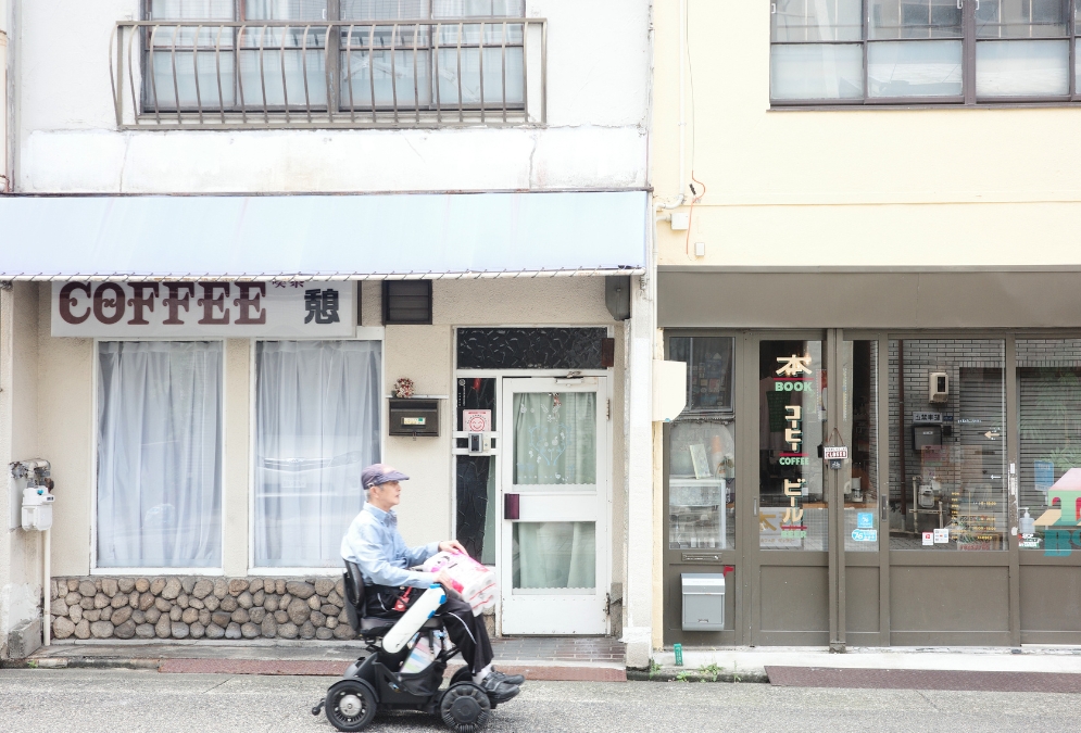 名古屋市熱田区・沢上商店街の喫茶店と書店の並び、電動カートで通り過ぎる男性