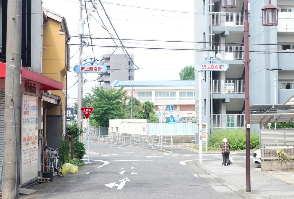 沢上商店街の入り口付近(名古屋・熱田区)、歩行器を押すおばあさんと団地のある風景