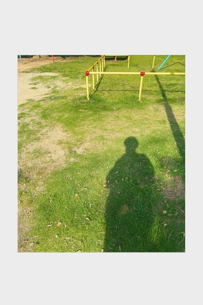 名古屋の公園に差し込む夏の光と鉄棒に映る人物の影。