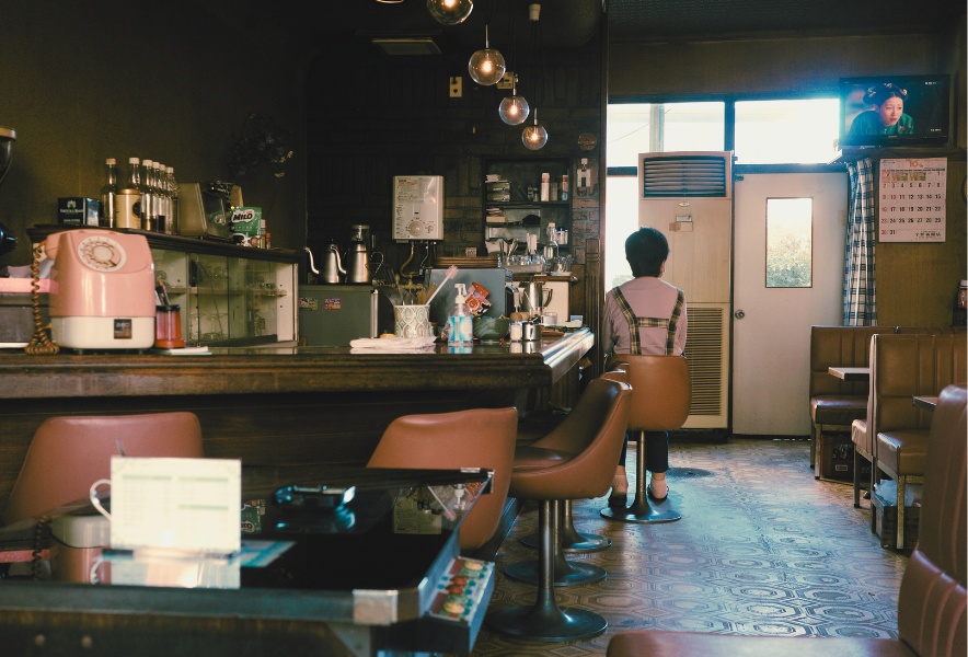 名古屋市千種区にある喫茶らんのカウンター席と店内全景。奥のテレビと 店主の後ろ姿が残る風景