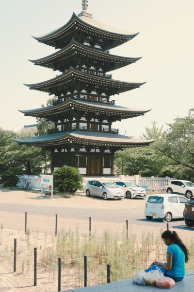 覚王山日泰寺の五重塔を背景に、日差しを避けて座る女性の姿。