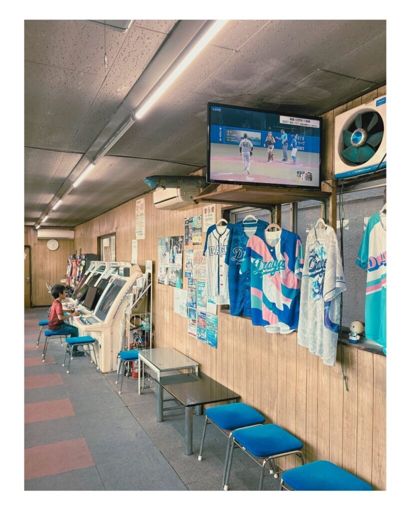 名古屋市上社の名古屋インターバッティングで。プロ野球中継が流れる店内。子どもたちはゲーム機に夢中で、大人たちは壁に飾られたドラゴンズのユニフォームを背に過ごす。
