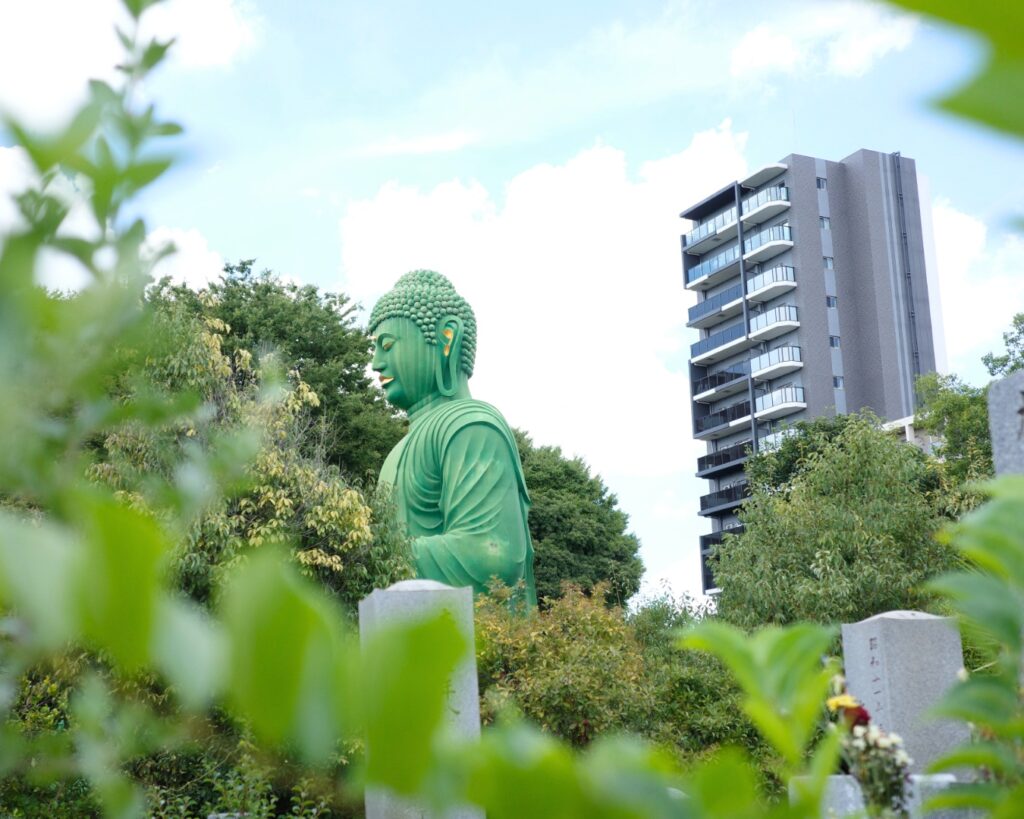 名古屋市千種区・桃厳寺の名古屋大仏。墓地とマンションを背景に、緑の大仏が存在感を放つ風景