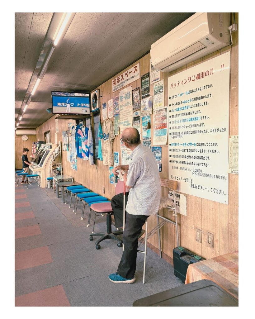 プロ野球中継が流れる名古屋インターバッティングの店内。年季の入ったゲーム機に向かう子どもと、ドラゴンズグッズが並ぶ壁。
