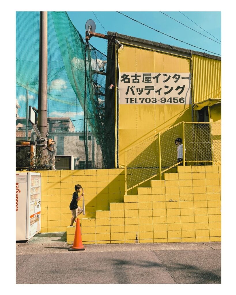名古屋市上社の名古屋インターバッティングの看板が掲げられた外観。黄色い階段を駆け上がる子どもが、時間の流れをつなぐ。