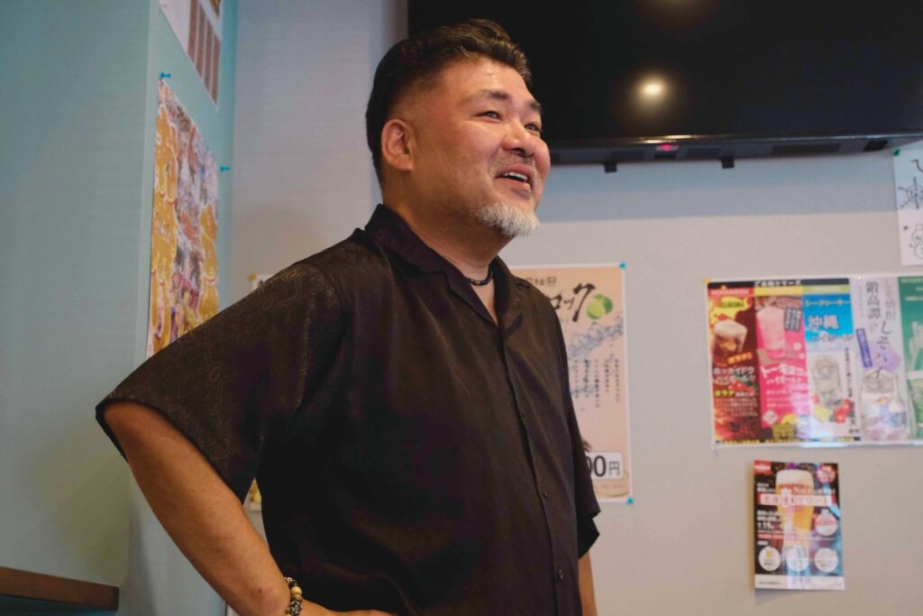 今池の居酒屋「せんべろ元気」を営む明山聡一郎さんが、店内で笑顔を見せながら語る姿。