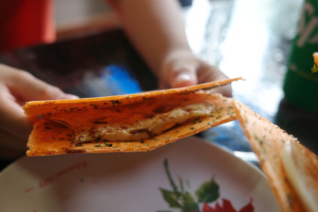 駄菓子屋「つねかわ」で提供される玉せんのクローズアップ。えびせんの間に挟まれた卵とソースの香ばしさが漂う。