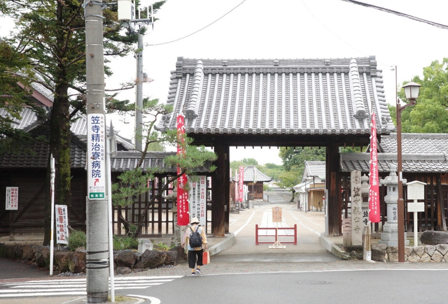 笠寺観音の山門に向かって歩く人の姿と、静かな境内へ続く参道。笠寺のまちの穏やかな気配が伝わる風景。
