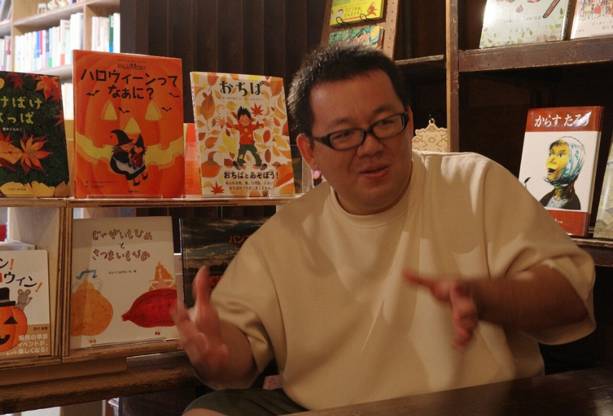 店内で話すブタコヤブックス店主・船張さん。子ども向けの本に囲まれながら、書店や地域について語る姿。