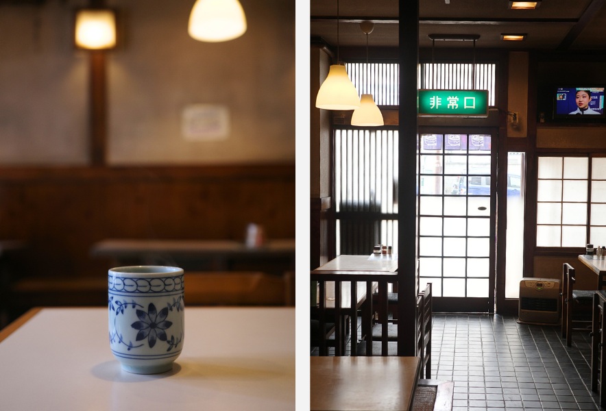 湯のみと木のテーブル、静かな店内の昼と店内入口の非常口表示｜仲田本通 めん処 森川屋