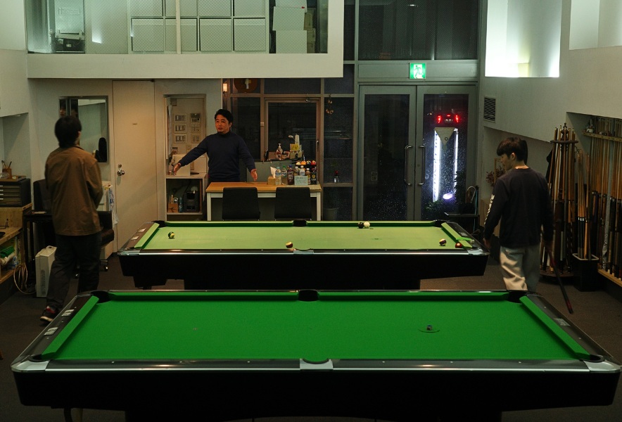 名古屋市昭和区・曙通りのビリヤード場「友楽」。夜の店内、テーブルを囲む人たちのゆるやかな時間。