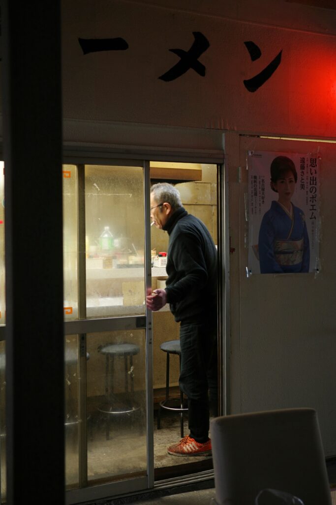 名古屋市中川区のタクちゃんラーメンの店主が厨房に立つ様子と夜の店構え