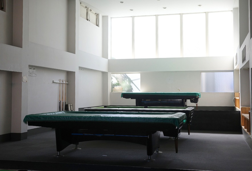 名古屋市昭和区・曙通りのビリヤード場「友楽」。白い壁と大きな窓に囲まれた、奥行きのある開放的なフロア。
