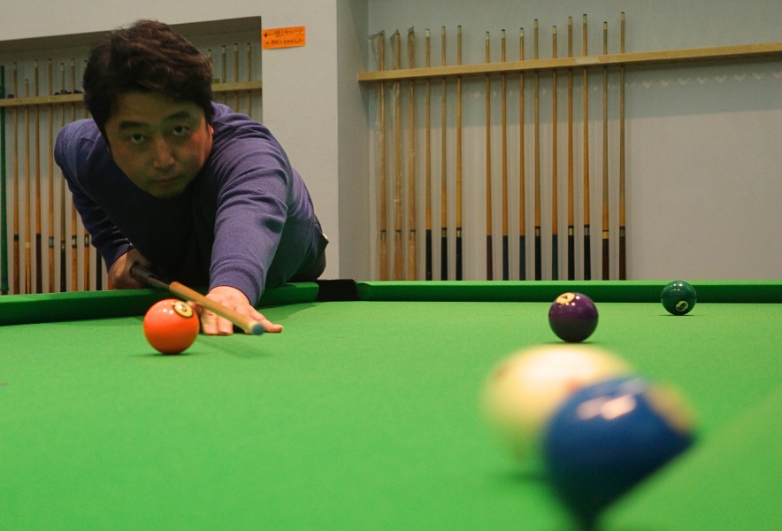 名古屋市昭和区・曙通りのビリヤード場「友楽」。ビリヤード台に身を乗り出し、静かにショットを狙うひととき。