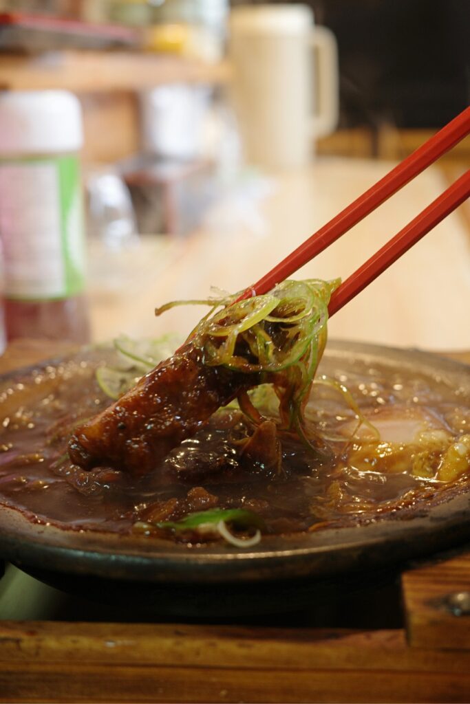 名古屋市千種区 もり川 味噌かつ鍋を箸で持ち上げる様子