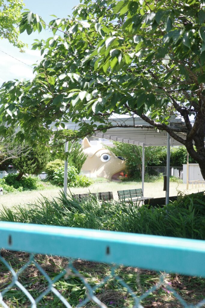若葉児童遊園地の木々の向こうから顔をのぞかせる巨大な犬型消防団詰所。