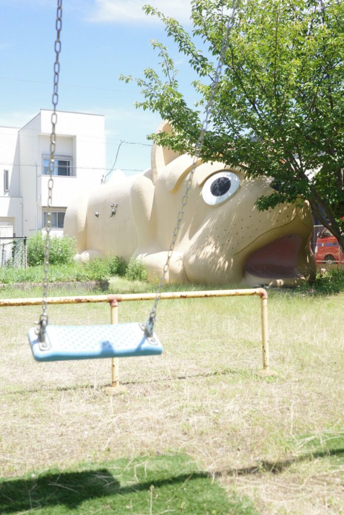 ブランコの向こうに鎮座する巨大な犬型消防団詰所。昭和区白金の住宅街に残る不思議な風景。