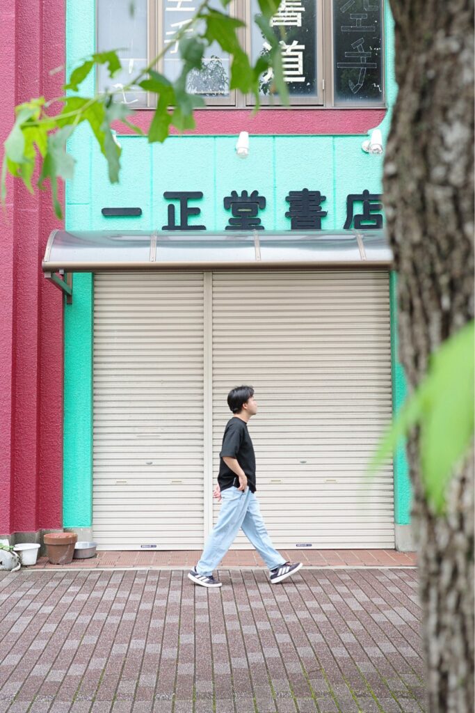 店の前の歩道を歩く通行人、シャッターが閉まった店舗