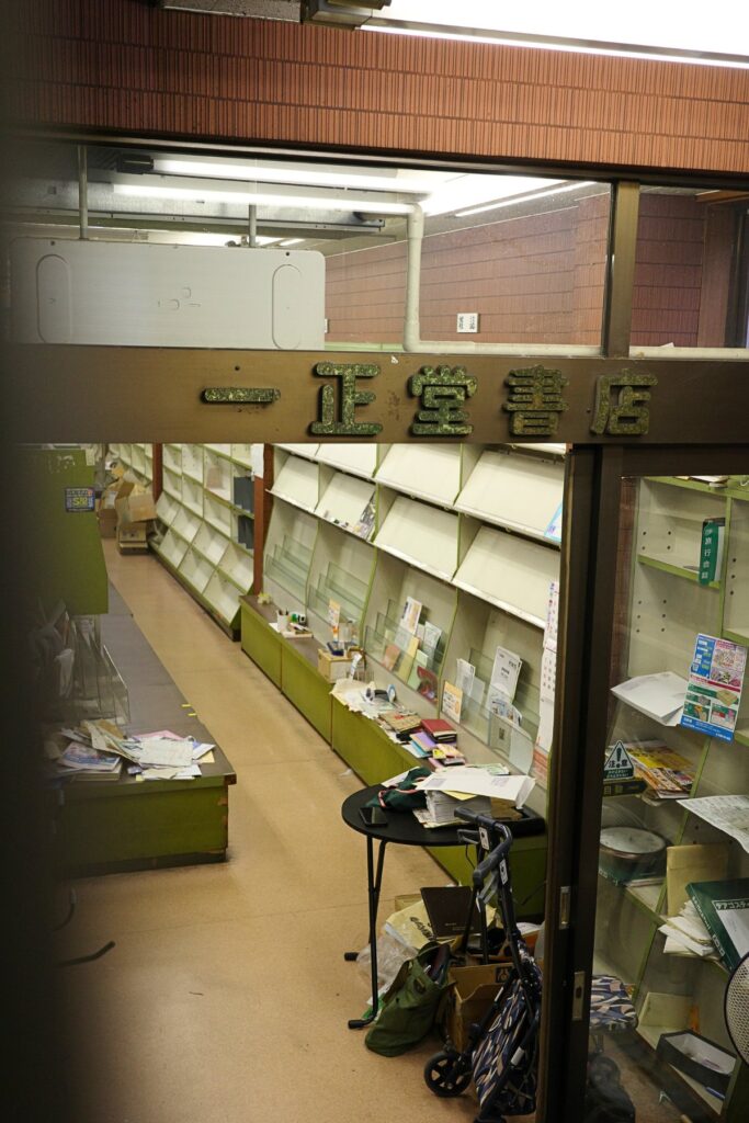 一正堂書店の看板と、空の棚が並ぶ店内