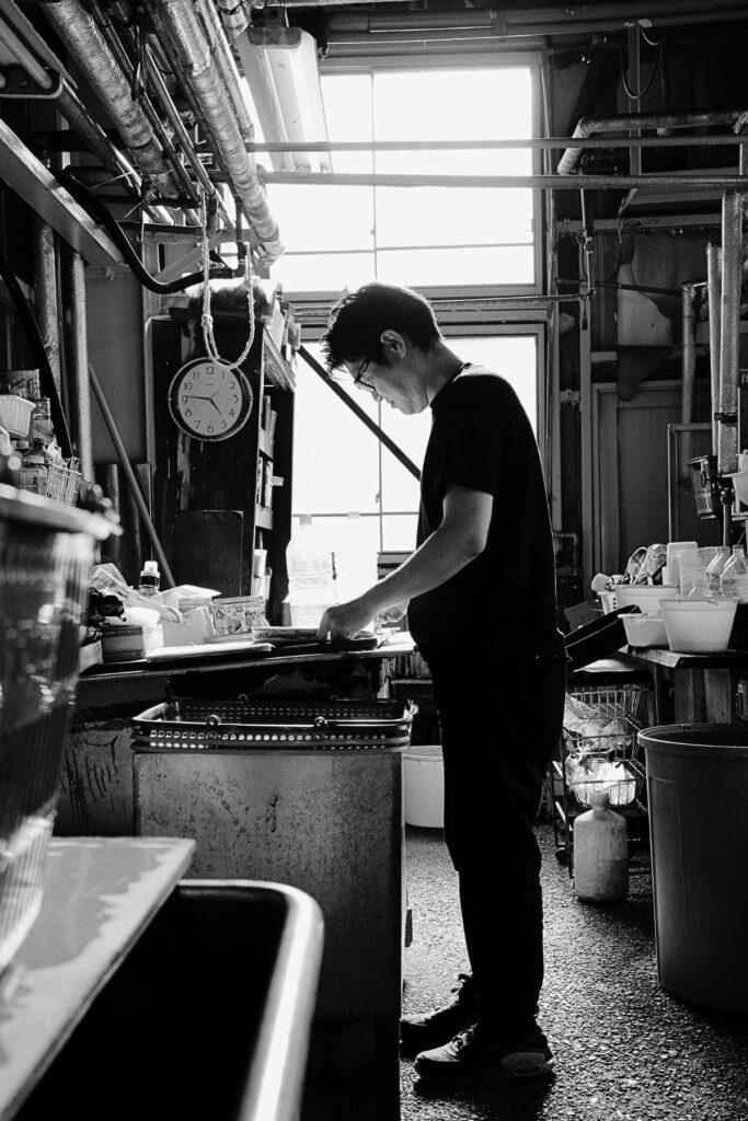 名古屋黒紋付染の工程を確認する山勝染工4代目・中村剛大さん。伝統工芸の現場風景