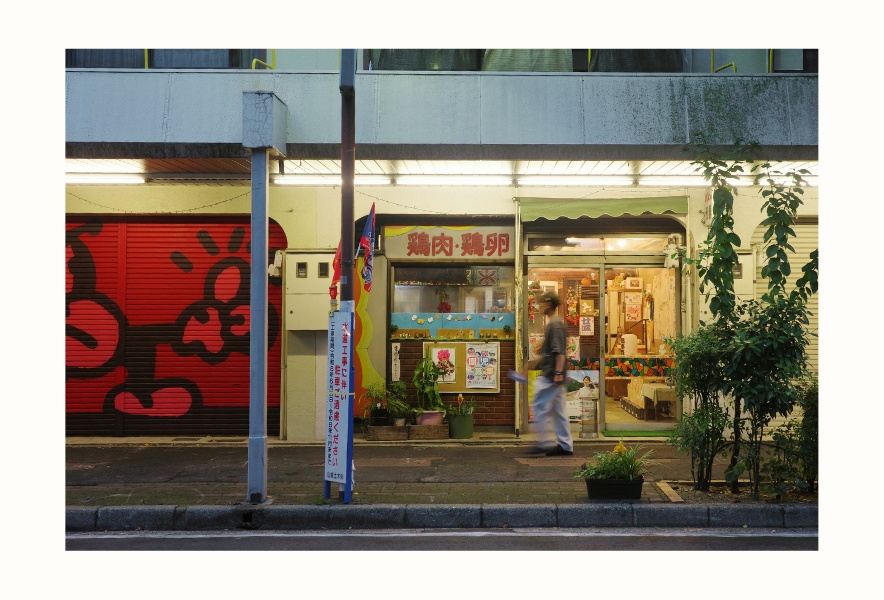 名古屋市南区・内田橋商店街の昔ながらの鶏肉店「浅藤商店」。グラフィティが描かれたシャッターと、店先を歩く人。