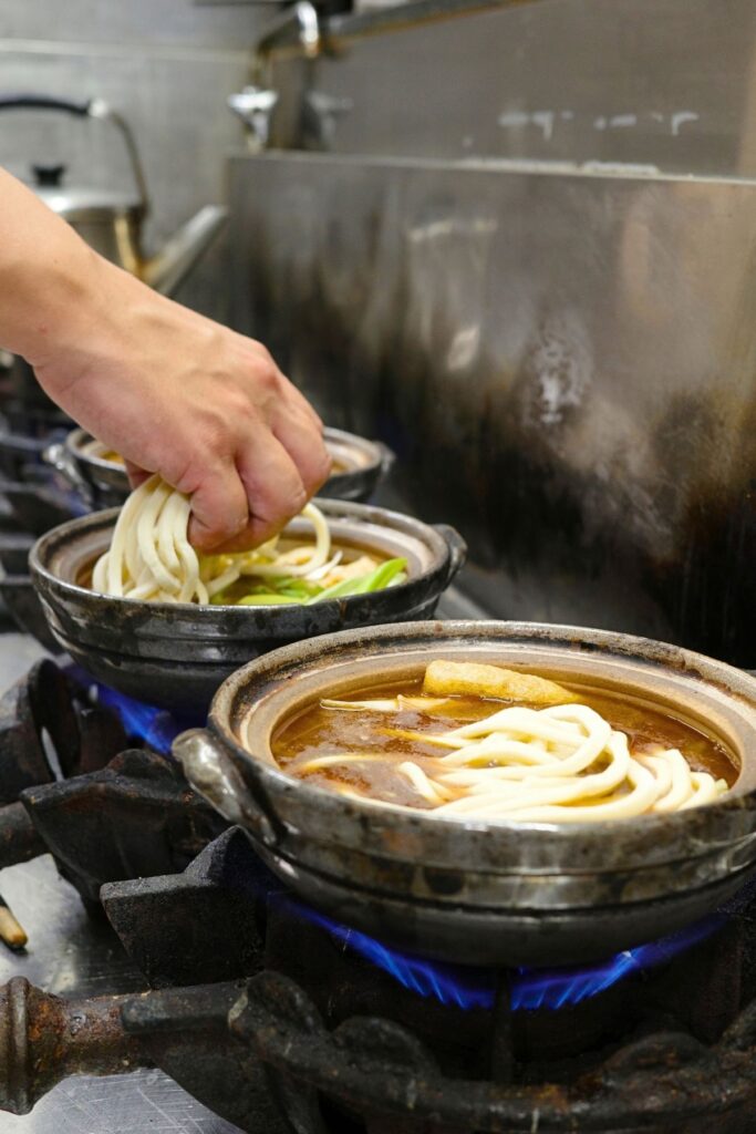 土鍋の味噌だしに手打ちうどんを入れる、山本屋大久手店の厨房