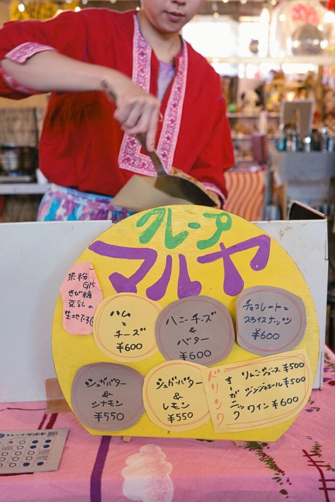 金城朝市に出店する「クレープマルヤ」の手書きメニュー看板。米粉ときび糖、豆乳を使った生地のクレープ