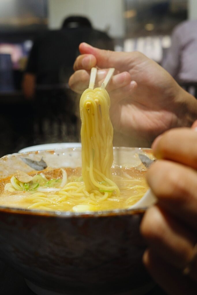 湯気の立つスープから持ち上げた、八龍の味噌ラーメンの中太ストレート麺