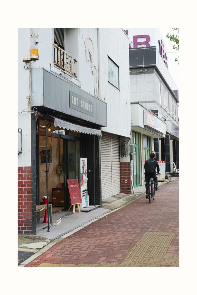 名古屋市南区のギャラリー「ART STUDIO」。古い建物を利用した店舗の前を自転車で通り過ぎる人。
