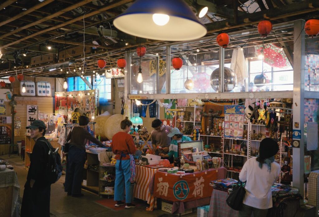 金城市場の中に並ぶ雑貨や古道具の店。赤い提灯と昔の精肉店の看板が残る
