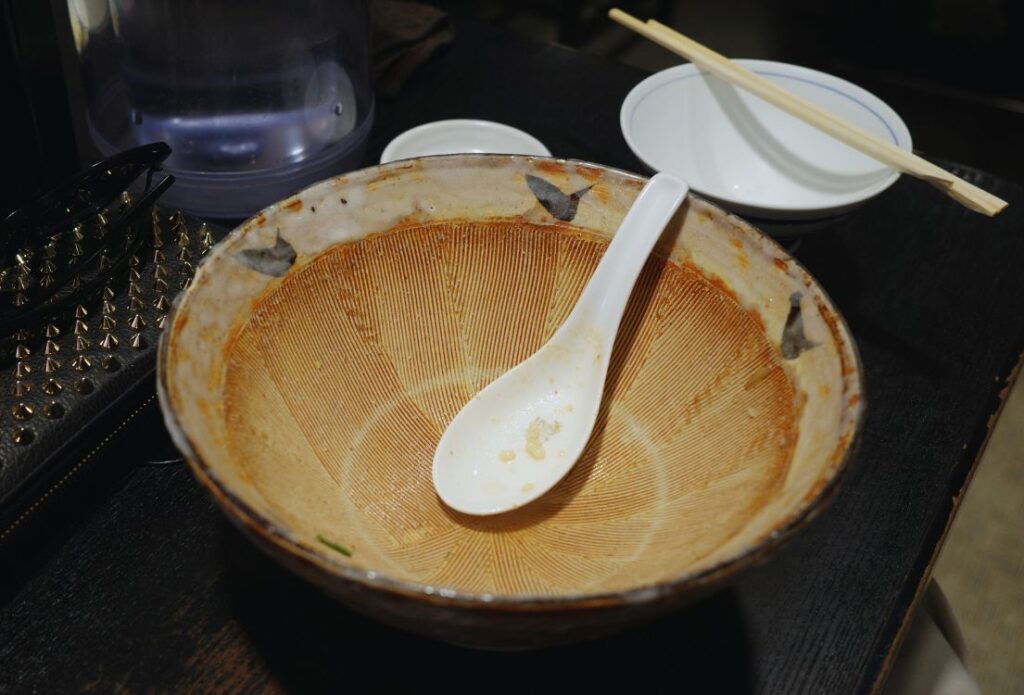 スープまで食べ終えた八龍の味噌バターラーメンの丼とレンゲ